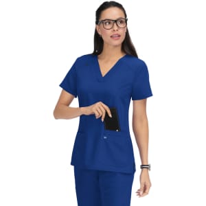 A blue scrub top with a V-neck and two front pockets, worn by a woman with glasses. The top features a logo.