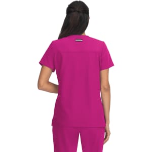 A woman wearing a vibrant pink top, viewed from the back, with a simple design and a logo on the upper back.
