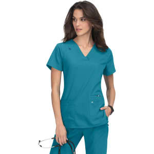A teal scrub top with a V-neckline and two front pockets, worn by a model holding glasses.
