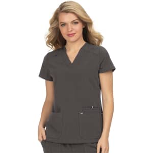 A woman wearing a grey medical scrub top with a v-neck and two front pockets. The top features a subtle pattern.