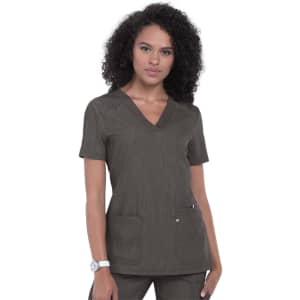 A woman wearing a short-sleeved, dark brown scrub top with two pockets, featuring a subtle textured design.