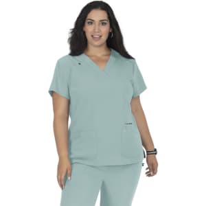 A top in a soft teal colour, featuring short sleeves, a V-neck, and two front pockets. It has a branding logo.