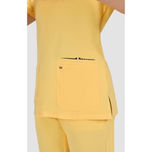 A yellow top with short sleeves and a pocket, featuring a logo, displayed on a model against a grey background.