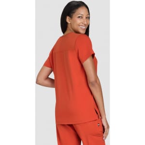 An orange top with short sleeves, featuring a back cutout and side slits, worn by a model from behind.