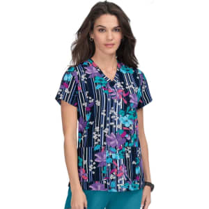 A floral print scrub top featuring a navy background with vibrant purple, pink, and white patterns. It has a logo.