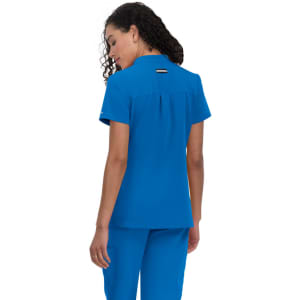 A blue medical scrub top with a back pleat and a logo, featuring short sleeves and a collar.