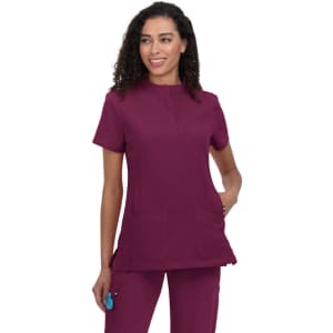 A scrub top in burgundy with a rounded neckline and two front pockets, featuring a branding logo.