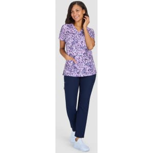 A printed purple top with short sleeves, paired with navy pants, and worn with light blue shoes.