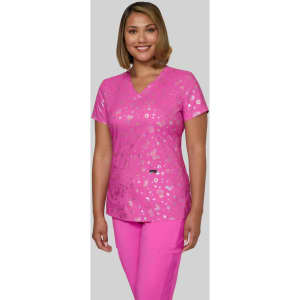 A pink scrub top featuring a floral print, worn by a model. The top has a V-neck and a logo on it.