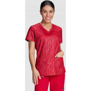 A woman wearing a red printed top, featuring a V-neck and two front pockets, complemented by red pants.