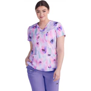 A woman wearing a vibrant lavender and pastel print top with short sleeves and two front pockets.