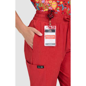 Red trousers with a side pocket, paired with a floral top. The trousers feature a brand label.