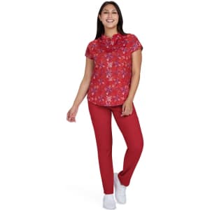 A floral print top in red, paired with red trousers and white shoes, worn by a smiling woman.