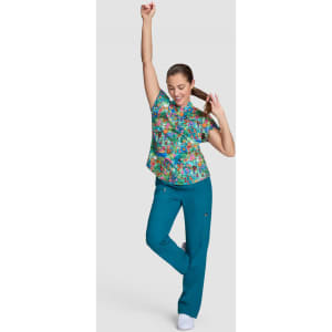 A medical top in a vibrant floral print paired with teal scrubs, featuring a model posing energetically.
