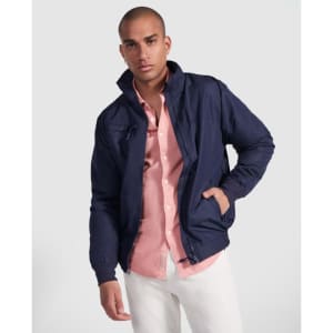 A navy waterproof jacket with a zip, featuring a collar and pockets, worn over a light pink shirt and white trousers.