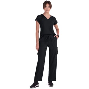 A person wearing a black top and black cargo pants, standing in a relaxed pose with a simple black logo visible.