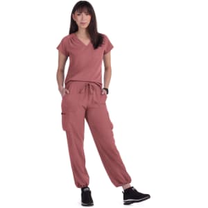 A woman wearing a rose-coloured top and matching cargo pants, with a pocket and jogger cuffs, paired with black sneakers.