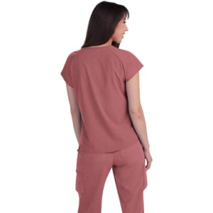 A woman in a pink top is shown from behind, wearing matching pants. The outfit has a relaxed fit and short sleeves.