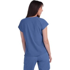 A woman wearing a blue top, viewed from the back, with short sleeves and a relaxed fit. The top includes a logo.