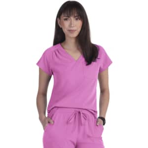 A pink scrub top features short sleeves and a V-neck design with a pocket on the front. Brand logo present.