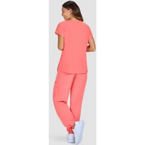 A set of women's scrubs in a bright coral colour, featuring a short-sleeve top and elastic waistband pants.
