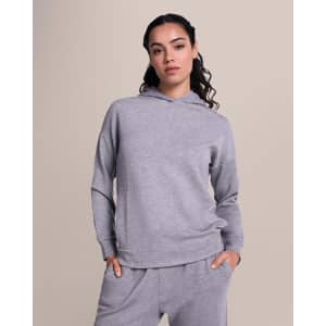 A grey hoodie with a relaxed fit and a hood, worn by a model against a neutral background.