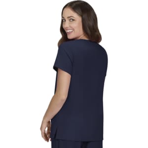 A woman wearing a navy top with a short sleeve and a relaxed fit, looking back and smiling.