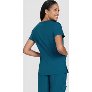 A woman is wearing a teal top, looking back with a smile, featuring a fitted design and short sleeves.