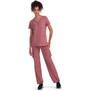 A set of scrub clothing in dusty pink, featuring a short-sleeve top with pockets and matching pants.