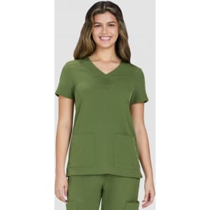 A green scrubs top featuring a V-neck, short sleeves, and two front pockets. The model is smiling.