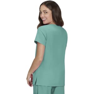 A woman smiles while wearing a teal top with short sleeves, featuring a relaxed fit and side slits.