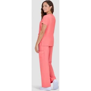 A woman wearing a vibrant coral scrub set with a relaxed fit, featuring a top and cargo-style trousers.