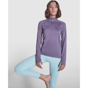 A purple women's sweatshirt with a half-zip design, paired with light blue leggings, features a logo on the chest.