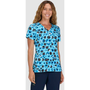 A woman wearing a blue v-neck top with a colourful print featuring various patterns. The top has a logo.