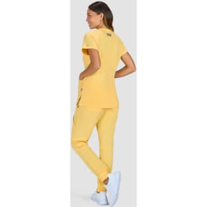 A model wearing a yellow top and matching pants, with white shoes, facing away from the camera.