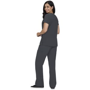 A woman wearing a grey Sari Top and matching cargo pants, smiling and seen from the back. The outfit has a logo.