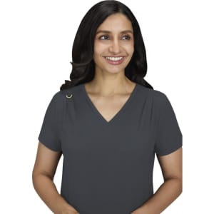 A woman smiles while wearing a charcoal grey Sari Top with a V-neck and short sleeves. The top features a small logo.