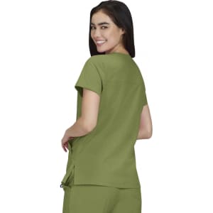 A woman wearing an olive green Sari Top, showcasing the back view of the shirt. The product has a logo.