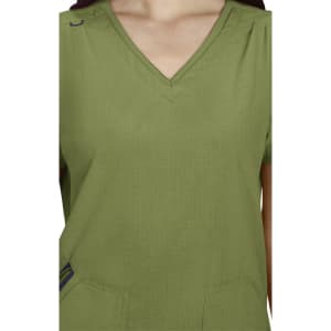 A green Sari Top with a V-neck and short sleeves, featuring subtle pleats and pockets. It has a small logo.