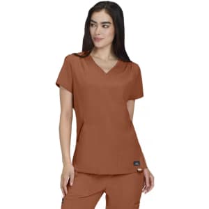 A woman models a brown Sari Top, featuring a V-neck and short sleeves, with pockets and a logo.