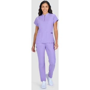 A medical uniform set in lavender featuring a short-sleeved top with a zip and matching trousers. It includes a logo.