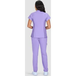 A woman wearing a lilac-coloured scrub set with a short-sleeve top and matching pants, viewed from the back.