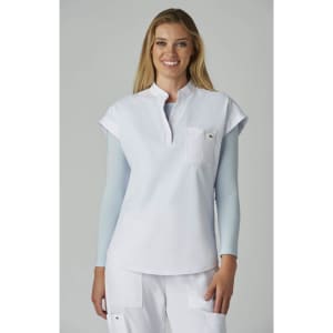 A white top with short sleeves and a front pocket, worn by a smiling woman against a neutral background.