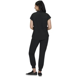 A black women’s outfit featuring a short-sleeve top and tapered pants, with a person standing from the back.