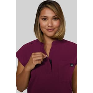 A short-sleeve women's top in a rich plum colour, featuring a zip neck and a small logo on the chest.