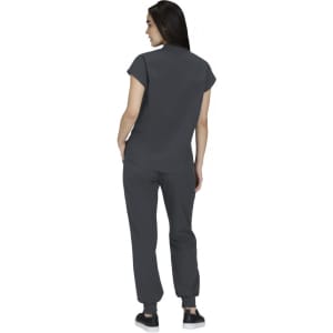 A woman in a grey top and matching grey pants, viewed from the back, wearing casual shoes. A logo is visible.