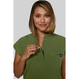 A green Catrin Top featuring a collar and a zippered neckline, paired with a logo.