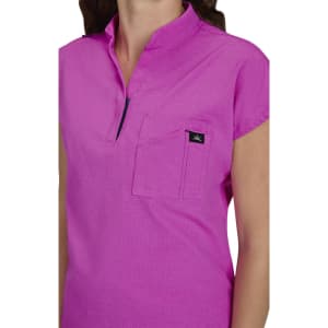 A pink women's top featuring a collar, short sleeves, and a breast pocket. The top includes a logo on the pocket.