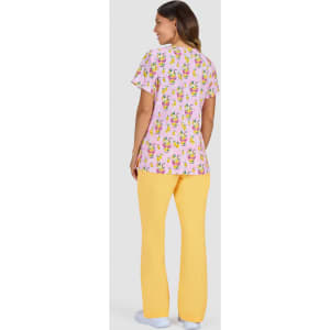 A woman wearing a pink top with a colourful print and yellow pants, seen from the back. The outfit features a logo.