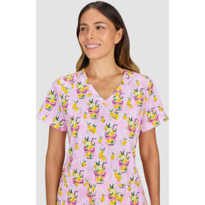 A pink scrub top with a playful print featuring drinks and fruit designs. The top has a V-neck and short sleeves.